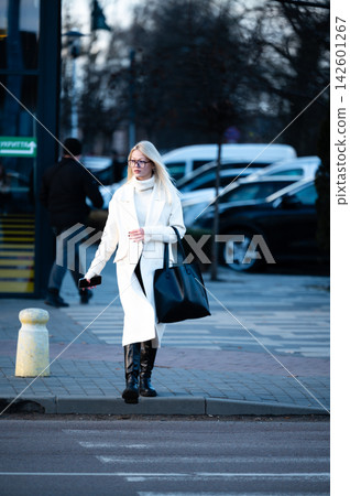 Stylishly crossing the street on a chilly evening in a vibrant urban setting with elegant fashion and gentle winter light Stylishly crossing the street on a chilly evening in a vibrant urban setting with elegant fashion and gentle winter light 142601267