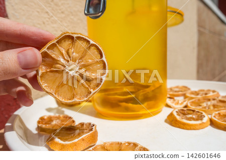 Hand Holding a Dried Lemon Slice with Jar and Plate of Dried Citrus Hand Holding a Dried Lemon Slice with Jar and Plate of Dried Citrus 142601646
