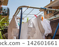 White laundry drying on a clothesline on a residential building balcony 142601661