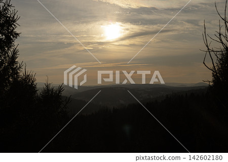 Sunset over mountain range with silhouette of evergreen trees Sunset over mountain range with silhouette of evergreen trees 142602180