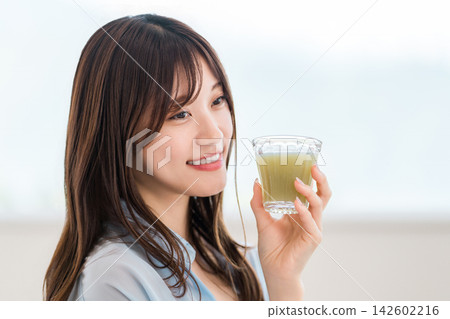 A young woman supplements her nutrition with a green smoothie. A healthy daily diet. A young woman supplements her nutrition with a green smoothie. A healthy daily diet. 142602216