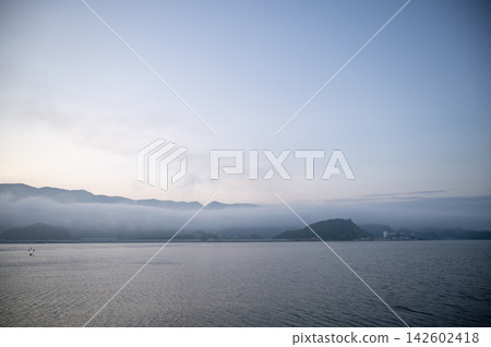 凌晨 4 點 30 分,初夏清晨,一片寧靜祥和的景象,夢幻般的晨霧低低地籠罩著大海和山麓。 凌晨 4 點 30 分,初夏清晨,一片寧靜祥和的景象,夢幻般的晨霧低低地籠罩著大海和山麓。 142602418