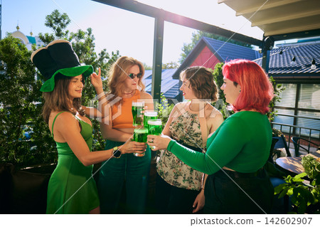 Stylish women chat with beer glasses during relaxed gathering on sunny urban terrace Stylish women chat with beer glasses during relaxed gathering on sunny urban terrace 142602907