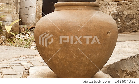 Traditional Clay Water Jar Outside a Rustic Village Alley Traditional Clay Water Jar Outside a Rustic Village Alley 142604352