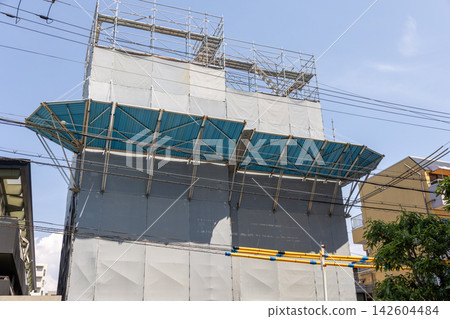 A building under construction, covered with temporary fencing and scaffolding. A building under construction, covered with temporary fencing and scaffolding. 142604484