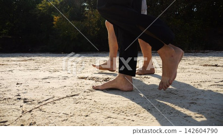 Male and female legs of pair walking on sandy beach. Bare feet of couple stepping along sand shore at sunny day. Lovers spending time together at resort. Concept of summer vacation or holiday Male and female legs of pair walking on sandy beach. Bare feet of couple stepping along sand shore at sunny day. Lovers spending time together at resort. Concept of summer vacation or holiday 142604790