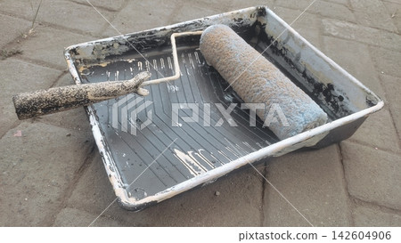 Paint Roller and Plastic Tray Resting on Paved Outdoor Surface Paint Roller and Plastic Tray Resting on Paved Outdoor Surface 142604906