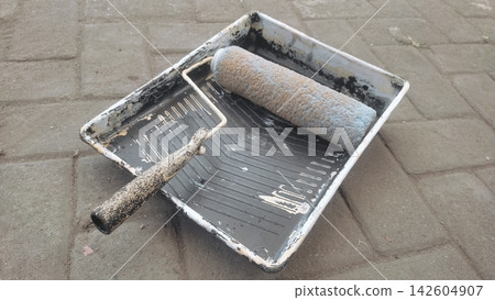 Paint Roller and Plastic Tray Resting on Paved Outdoor Surface Paint Roller and Plastic Tray Resting on Paved Outdoor Surface 142604907