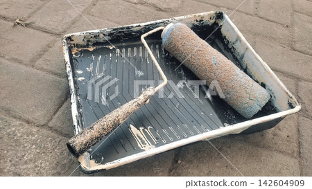 Paint Roller and Plastic Tray Resting on Paved Outdoor Surface Paint Roller and Plastic Tray Resting on Paved Outdoor Surface 142604909