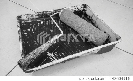 Monochrome Image of Paint Roller and Tray Resting on Paved Ground Monochrome Image of Paint Roller and Tray Resting on Paved Ground 142604916