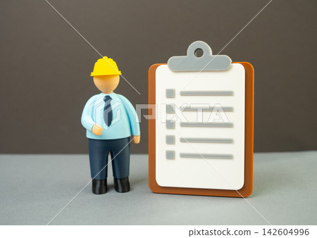 Engineer and paper clipboard with criteria checklist, workplace safety briefing, design and planning concept. Technical inspection, project evaluation, construction standards Engineer and paper clipboard with criteria checklist, workplace safety briefing, design and planning concept. Technical inspection, project evaluation, construction standards 142604996