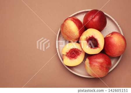Fresh ripe nectarine on plate on brown background. Space for text Fresh ripe nectarine on plate on brown background. Space for text 142605151