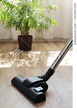 Cleaning the floor with a vacuum cleaner. Vertical photo Cleaning the floor with a vacuum cleaner. Vertical photo 142605169