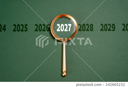 Year 2027 in focus of magnifying glass, future forecast concept. Looking ahead supports business planning, economic analysis and strategic decisions about opportunities, risks Year 2027 in focus of magnifying glass, future forecast concept. Looking ahead supports business planning, economic analysis and strategic decisions about opportunities, risks 142605232
