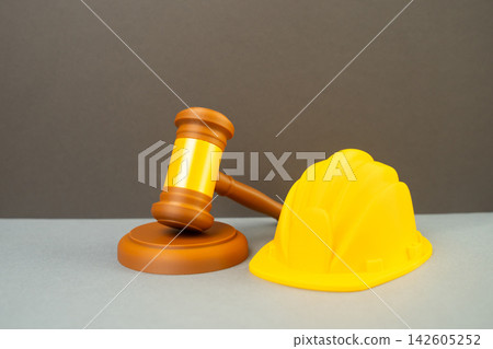 Construction helmet and judge's gavel, lawsuit over construction and construction works. Legal disputes, contractor responsibility, building regulations and court proceedings related to development Construction helmet and judge's gavel, lawsuit over construction and construction works. Legal disputes, contractor responsibility, building regulations and court proceedings related to development 142605252