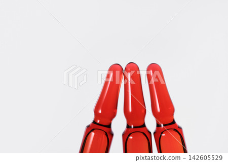 Three glass ampoules filled with red pharmaceutical liquid on white background Three glass ampoules filled with red pharmaceutical liquid on white background 142605529