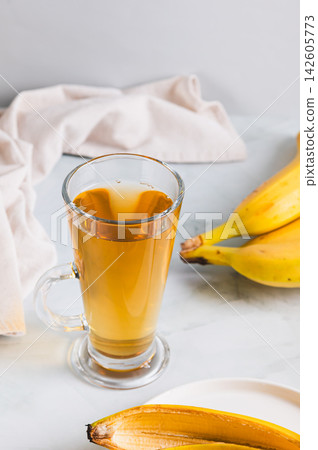 Evening sleep drink made from banana peel in a glass on the table vertical view Evening sleep drink made from banana peel in a glass on the table vertical view 142605773