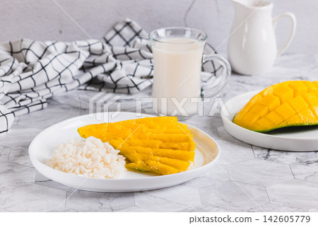 Making a trendy dessert of mango, rice, and coconut milk on a plate on the table 142605779