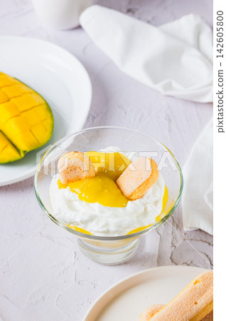 Mango trifle with savoiardi in a bowl on the table vertical view Mango trifle with savoiardi in a bowl on the table vertical view 142605800