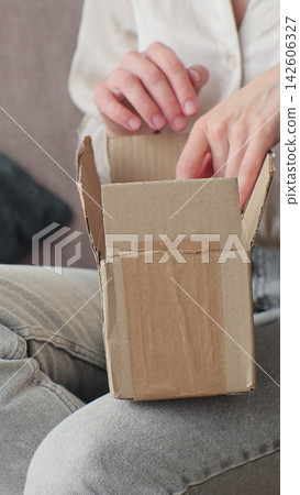 Vertical video. Woman opening package at home. Customer receiving online purchase, unpacking delivery. 142606327