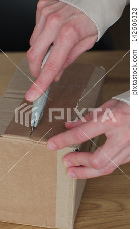 Vertical video. Woman consumer cutting order box on table at home room. Closeup view of female cuts cardboard and uses knife in hand. Happy client of online retailer concept. Vertical video. Woman consumer cutting order box on table at home room. Closeup view of female cuts cardboard and uses knife in hand. Happy client of online retailer concept. 142606328