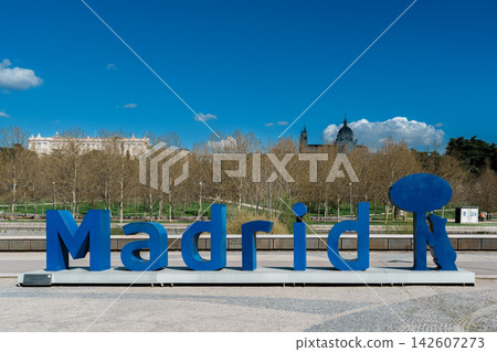 Blue Madrid city sign sculpture with Royal Palace and Almudena Cathedral in the background Blue Madrid city sign sculpture with Royal Palace and Almudena Cathedral in the background 142607273