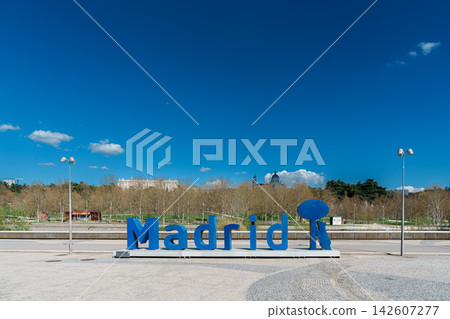 Blue Madrid city sign sculpture with Royal Palace and Almudena Cathedral in the background Blue Madrid city sign sculpture with Royal Palace and Almudena Cathedral in the background 142607277