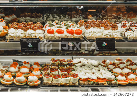 Display case of burrata and mozzarella tapas topped with tomato, pesto, and cured ham in a Mercado de San Miguel Display case of burrata and mozzarella tapas topped with tomato, pesto, and cured ham in a Mercado de San Miguel 142607278
