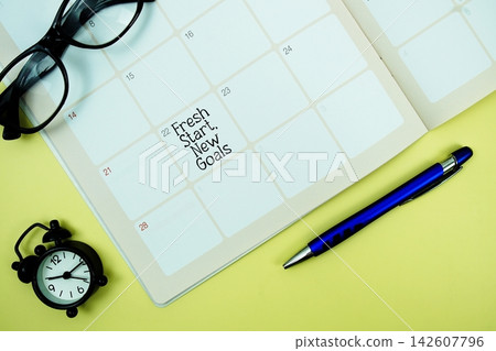Fresh Start, New Goals message written on calendar date with alarm clock, glasses and magnifying glass on yellow background Fresh Start, New Goals message written on calendar date with alarm clock, glasses and magnifying glass on yellow background 142607796