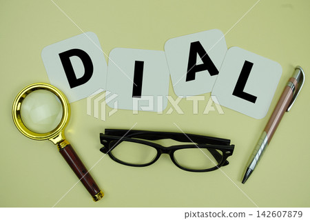 DIAL alphabet letters with magnifying glass, eye glasses and pen on yellow background DIAL alphabet letters with magnifying glass, eye glasses and pen on yellow background 142607879