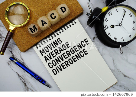 MACD Moving Average Convergence Divergence text written on notepad with magnifying glass and alarm clock on marble background MACD Moving Average Convergence Divergence text written on notepad with magnifying glass and alarm clock on marble background 142607969