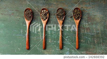 Assortment of Loose Leaf Teas in Wooden Spoons on Rustic Background Assortment of Loose Leaf Teas in Wooden Spoons on Rustic Background 142608392