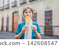 Boy holding a golden molote poblano traditional fried Mexican empanada outdoors on a street in Puebla Mexico with colonial city background paper wrapper local street food authentic travel snack. 142608547