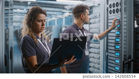IT Specialists Collaborating on Laptop in Data Center Server Room IT Specialists Collaborating on Laptop in Data Center Server Room 142608554