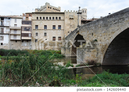 Stone bridge over river with old town buildings in background 142609440