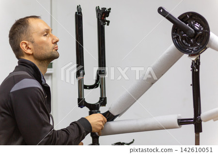 Mechanic assembling a bicycle frame in a workshop Mechanic assembling a bicycle frame in a workshop 142610051