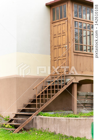 Weathered wooden entrance with tall windows and metal stairs Weathered wooden entrance with tall windows and metal stairs 142610108