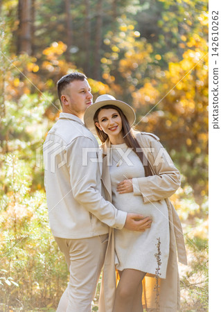 A loving couple poses together in a beautiful forest setting, celebrating their upcoming parenthood A loving couple poses together in a beautiful forest setting, celebrating their upcoming parenthood 142610262
