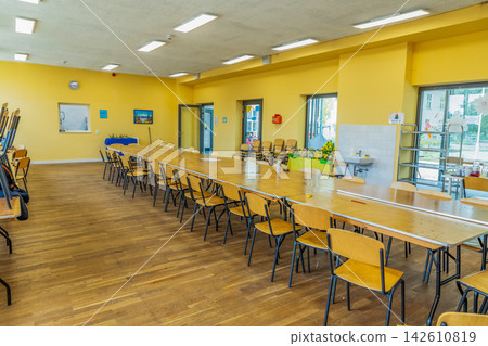 Bright communal dining area with long table and wooden chairs arranged Bright communal dining area with long table and wooden chairs arranged 142610819