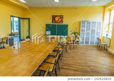 Bright classroom interior with large table, chairs, and chalkboard setup Bright classroom interior with large table, chairs, and chalkboard setup 142610820