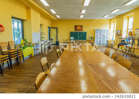 Spacious community room with wooden table and chairs arranged for gathering Spacious community room with wooden table and chairs arranged for gathering 142610821