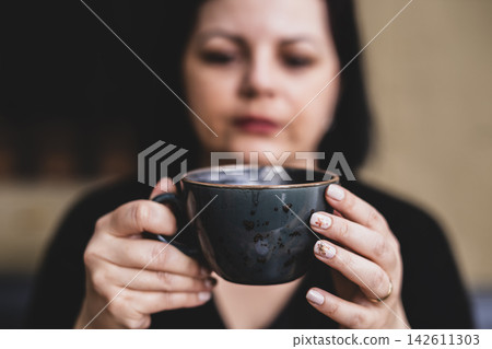 Woman Enjoying a Hot Beverage in a Coffee Shop.  142611303