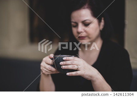 Woman Enjoying a Hot Beverage in a Coffee Shop.  142611304