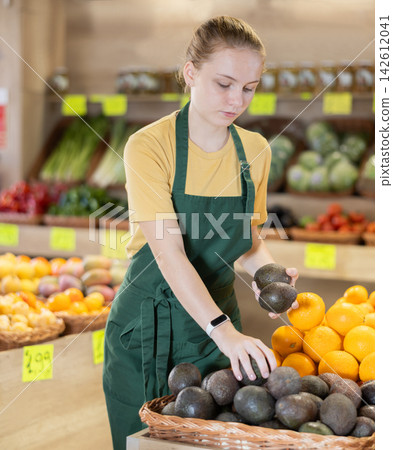 Young woman seller laying out avocado Young woman seller laying out avocado 142612041