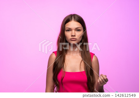 Young woman with an unhappy disappointed expression holding a shopping bag on a pink background Young woman with an unhappy disappointed expression holding a shopping bag on a pink background 142612549