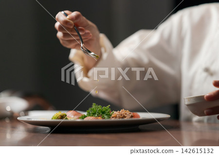The hands of a female chef pouring sauce. The hands of a female chef pouring sauce. 142615132