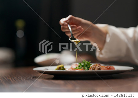女廚師正在倒醬汁。 女廚師正在倒醬汁。 142615135