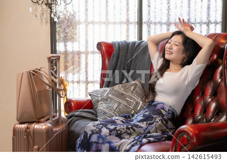A young woman relaxing on an antique sofa in a guesthouse. A young woman relaxing on an antique sofa in a guesthouse. 142615493