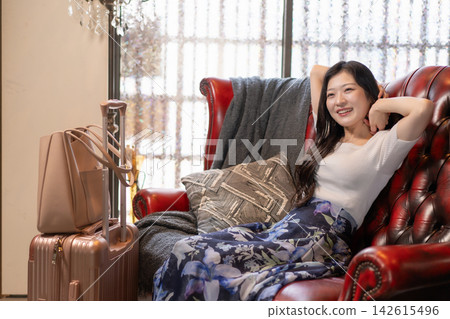 A young woman relaxing on an antique sofa in a guesthouse. A young woman relaxing on an antique sofa in a guesthouse. 142615496