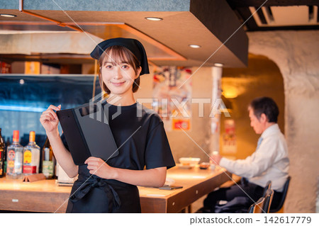 一位年輕的女服務生在居酒屋(日本酒吧)拿著帳單。 一位年輕的女服務生在居酒屋(日本酒吧)拿著帳單。 142617779